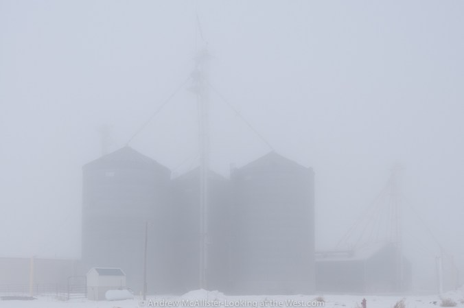 Photograph of grain silos in dense fog.